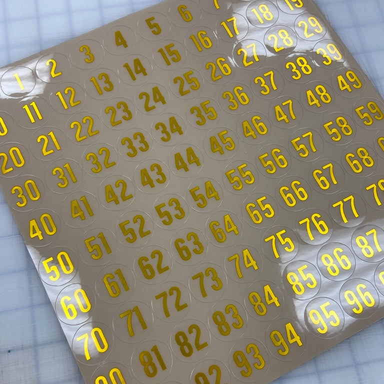Sheet of numbered stickers with yellow numbers on a grid background