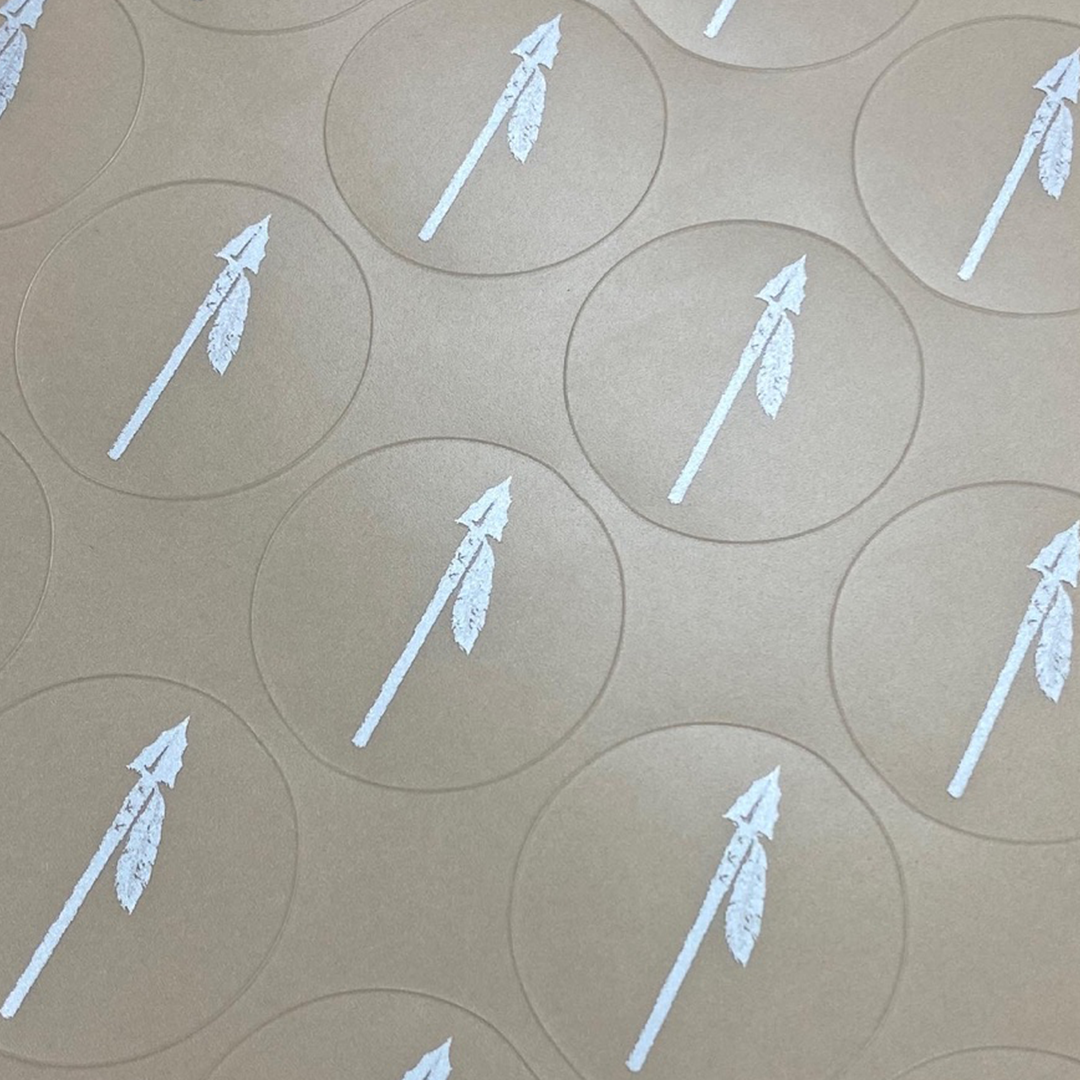 White arrow symbols on brown circular stickers