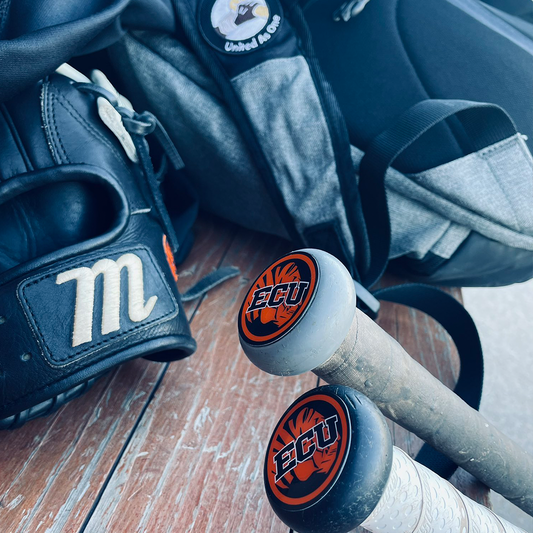 Baseball bat with ECU logo, glove, and backpack on a wooden surface