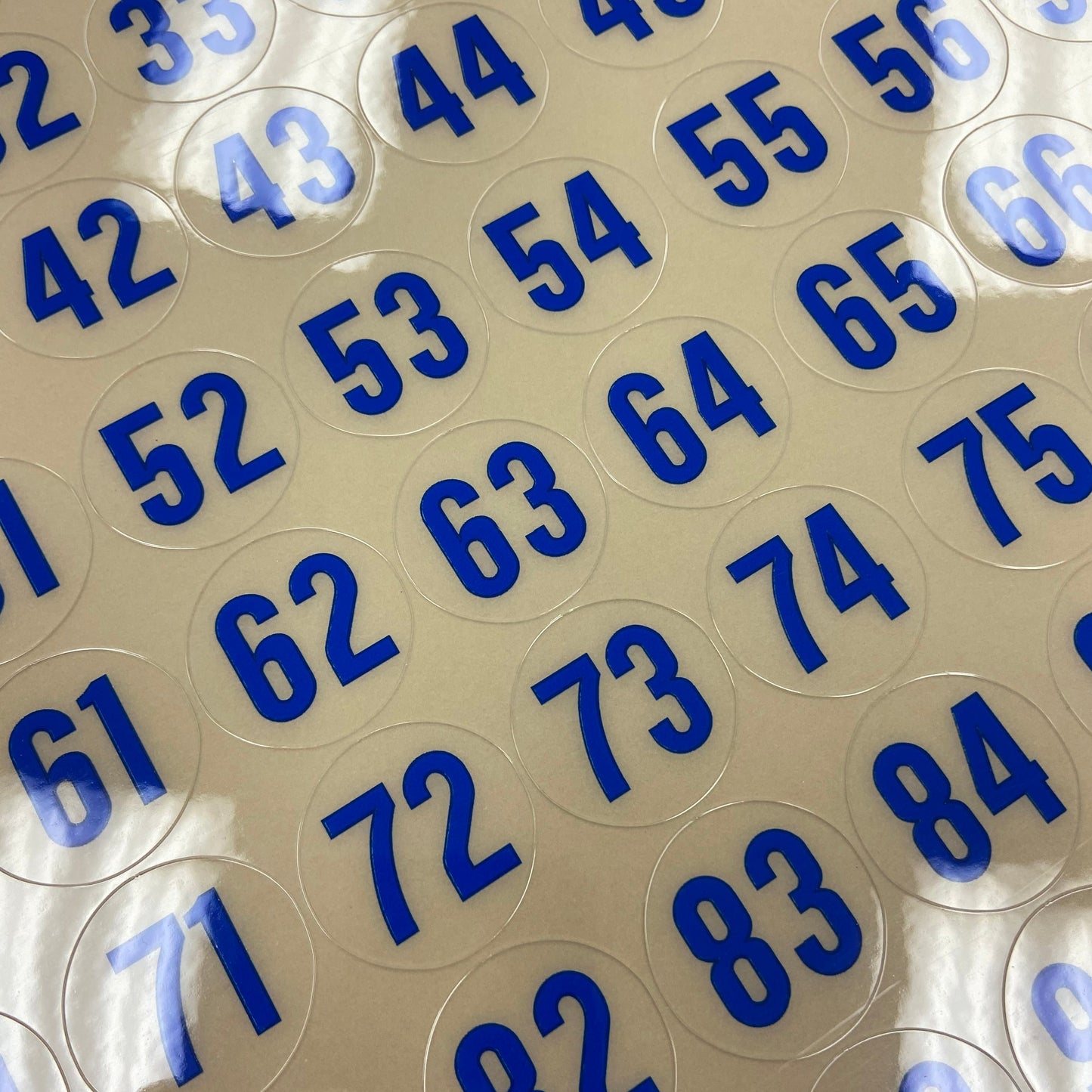 Close-up of round transparent stickers with blue numbers on a beige background