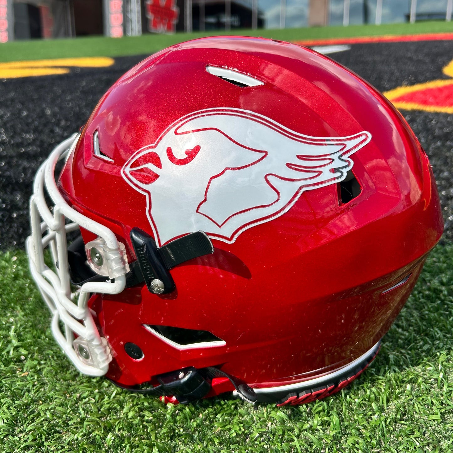 Red football helmet with a logo on a grass field